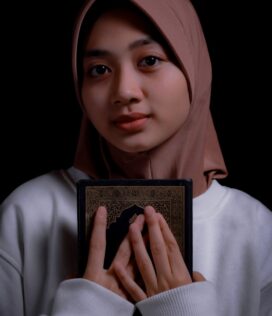 a woman in a hijab holding a book