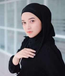 a woman wearing a black hijab standing in front of a building